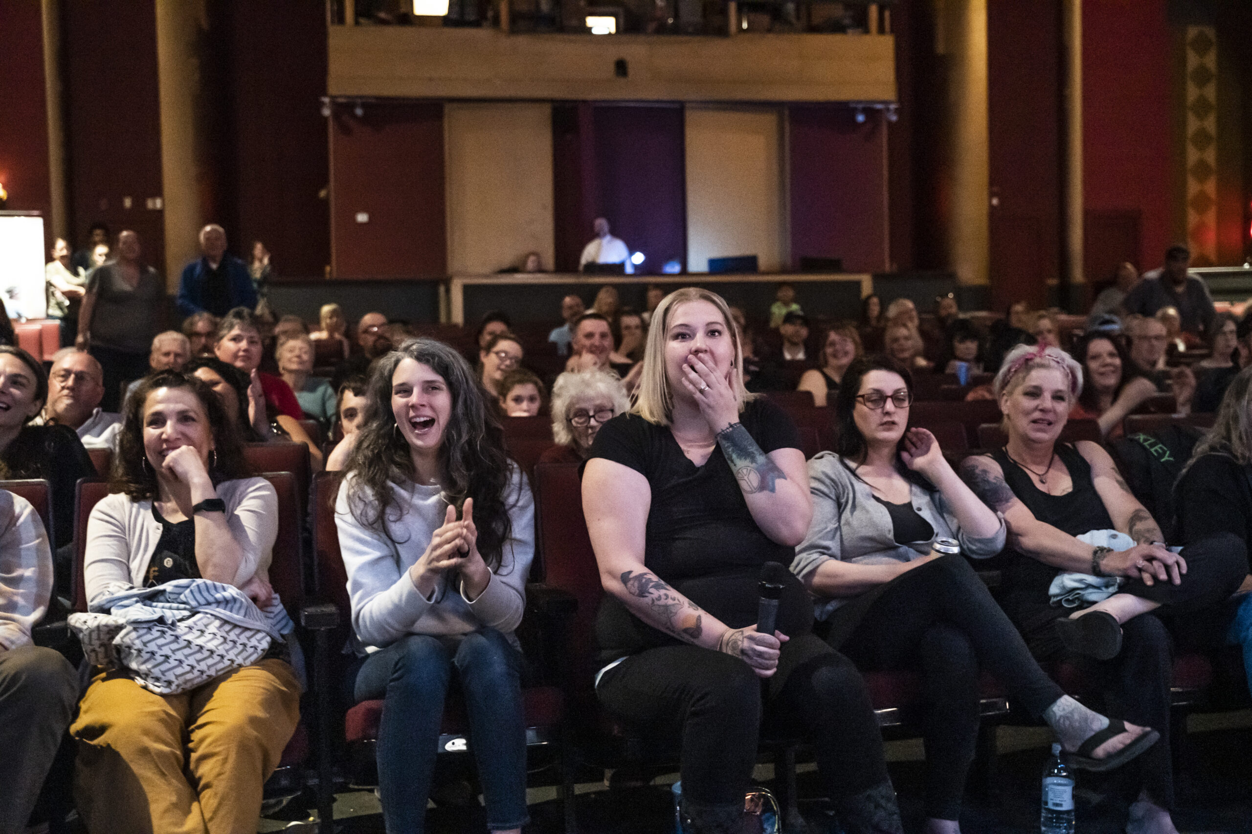 A theatre audience gasping and laughing mid-show