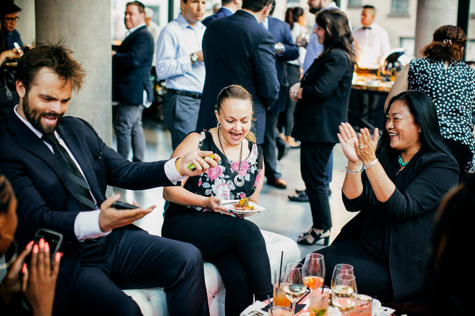Guests laughing and applauding during a close-up set at a corporate reception