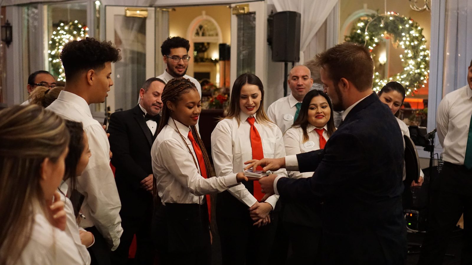 Kent Axell performing close-up card magic for restaurant staff at a holiday event
