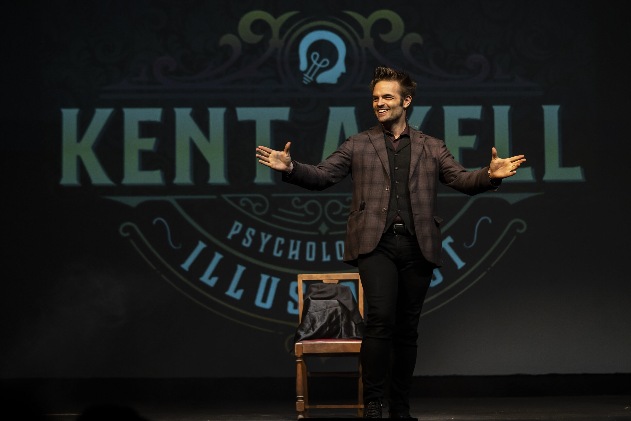 Kent Axell greeting the audience in front of his illuminated stage backdrop